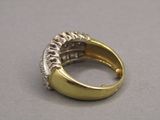 une image représentant une bague en or et en diamants posée sur une surface grise