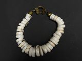 a close up of a bracelet with white beads on a black surface