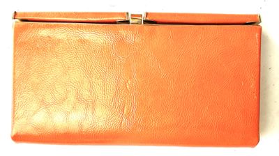 an orange leather purse with a metal clasp on a white background