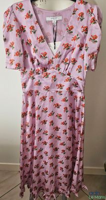 une robe rose à fleurs suspendue à un cintre dans une pièce