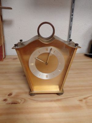 a gold clock sitting on top of a wooden table