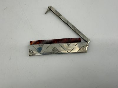 a metal comb with a wooden handle on a white surface