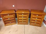 trois tables de chevet en bois avec des tiroirs dans une chambre dont l'un des murs est rouge