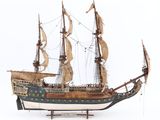 maquette en bois d'un grand voilier posée sur une surface blanche