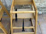 a wooden high chair next to a wooden chair on the ground