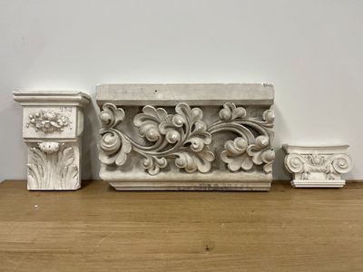 three decorative molds on a wooden shelf next to a white wall