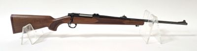 le fusil repose sur un support transparent posé sur une surface blanche