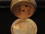 a gold pocket watch sitting on top of a black table