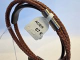 bracelet en cuir marron muni d'un fermoir en métal, présenté sur un présentoir noir
