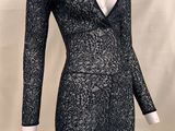 La robe est noire et argentée, avec un décolleté en V et des manches longues.