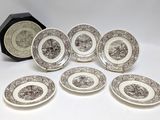 six brown and white plates with black and white designs and a clock