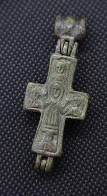 a close up of a silver cross on a black surface