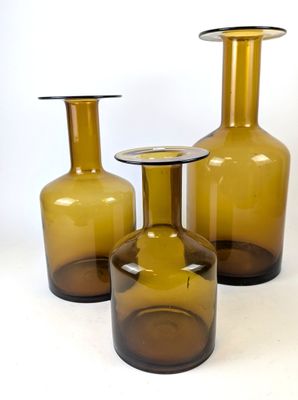 trois vases en verre brun posés les uns à côté des autres sur une surface blanche