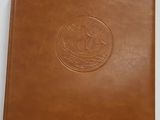 a brown leather album with a picture of a ship on it