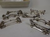 six silver plated hair clips sitting on a table next to a box
