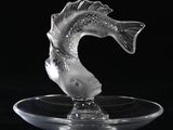 une sculpture en verre représentant un poisson, posée sur une assiette transparente