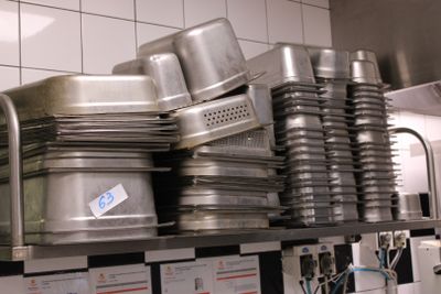 de nombreuses casseroles et poêles empilées sur une étagère dans une cuisine