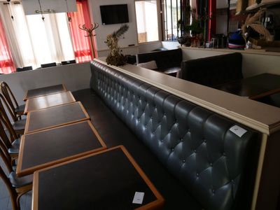 des tables et des chaises dans un restaurant, avec un bar en arrière-plan