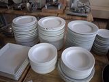 a lot of white plates on a table in the kitchen