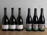 six bottles of wine are lined up on a wooden table