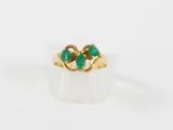 un gros plan d'une bague en or sertie de deux émeraudes