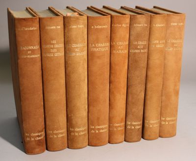 six old books are lined up in a row on a white surface
