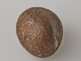 une vieille boule métallique posée sur une surface blanche, avec un fond gris