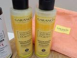 two bottles of lotion sitting on a table next to a towel