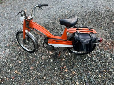 une trottinette orange avec un sac noir à l'arrière