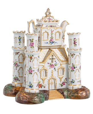 une théière blanche et dorée surmontée d'un château