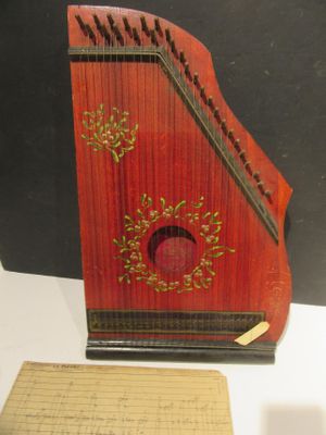 un petit instrument rouge posé sur une table, à côté d'une feuille de papier