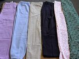 cinq paires de pantalons posées sur une table à côté d'une cravate
