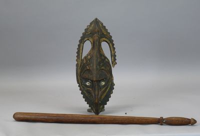 une image représentant un porte-bâton en bois sur lequel est posé un masque