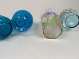 three different colored glass vases sitting on a white surface