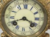 a gold clock with blue roman numerals on it