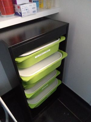 une étagère noire sur laquelle sont posés des récipients verts