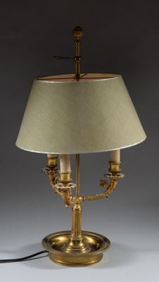 an antique brass table lamp with a beige shade on a white background