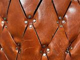 a close up of a brown leather chair with rivets on it