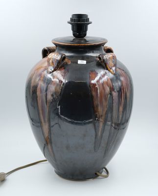 un vase noir et marron sur lequel est posée une lampe