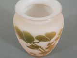 a white vase with a green leaf design on it