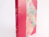 a red book with a pink cover sitting on a white surface
