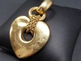 a close up of a gold heart pendant on a black pillow
