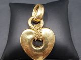 a gold heart charm sitting on top of a black pillow