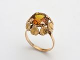 une image représentant une bague en or sertie d'une citrine facettée entourée de feuilles