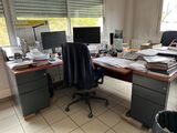 a desk with two computers and a chair in front of a window