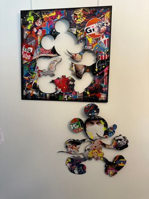 a man standing in front of a painting of mickey mouse
