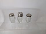three salt and pepper shakers sitting on a clear shelf