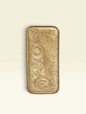 un vieux lingot d'or posé sur une surface blanche