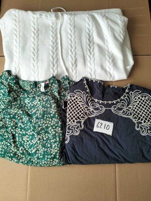 three tops and a bag sitting on top of a cardboard box