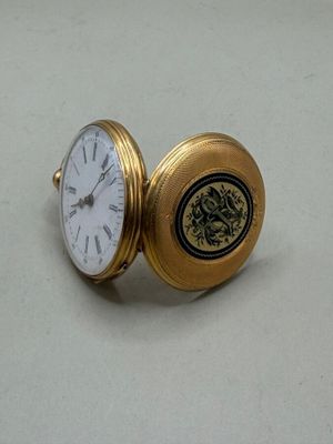 une montre de poche en or posée sur une surface blanche